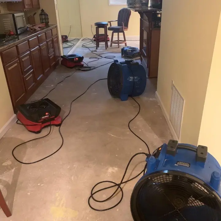 Air movers set up across a basement floor to dry the structure after flooring was removed